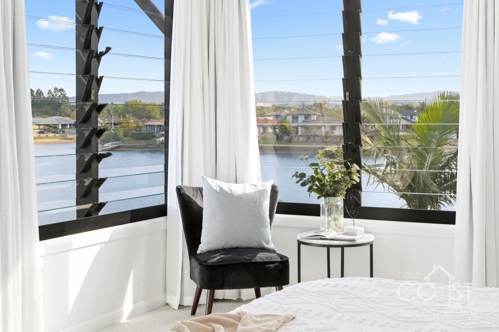A bedroom with a large window overlooking a lake.