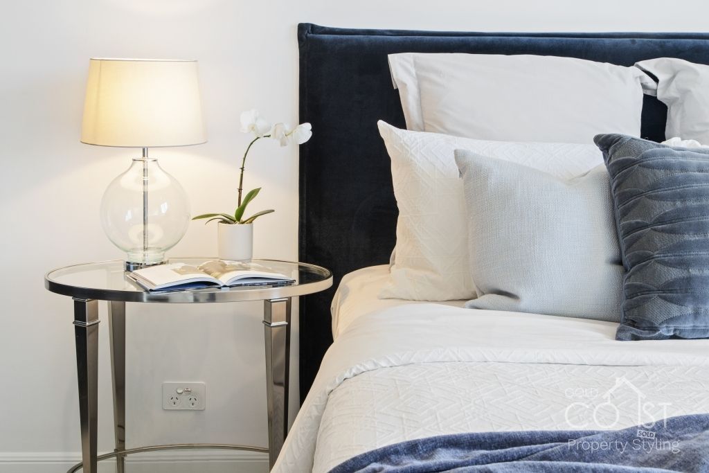 A bedroom with a bed , nightstand and lamp.