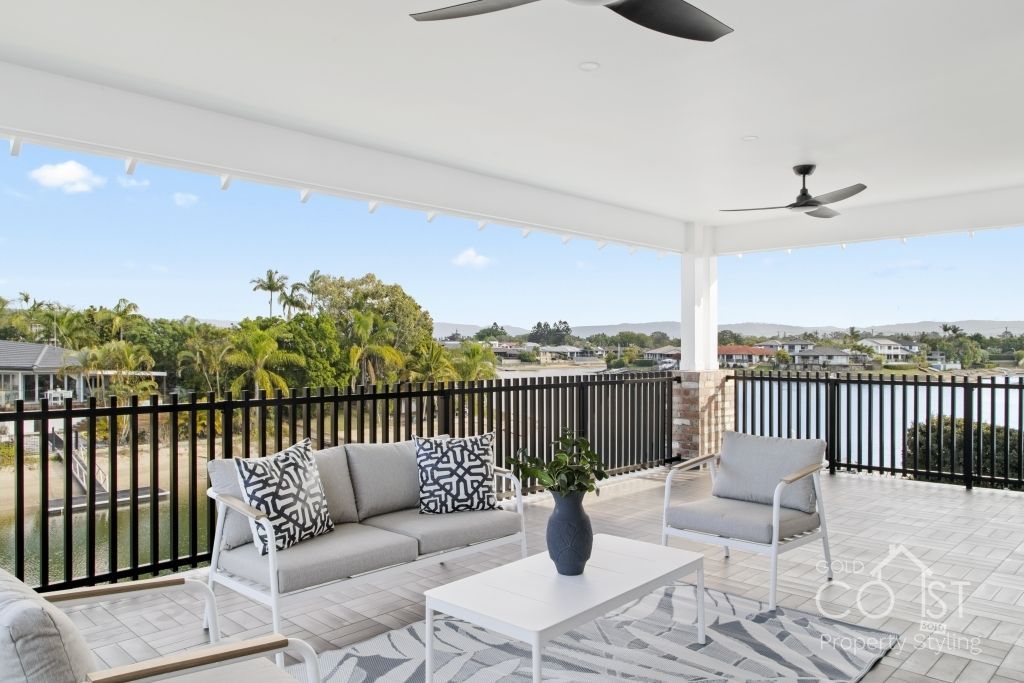 A balcony with a couch , chairs and a table with a view of a lake.