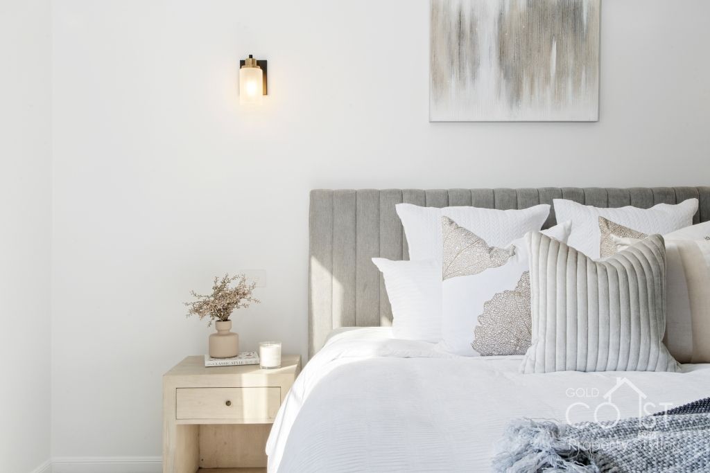 A bedroom with a bed , nightstand , and painting on the wall.