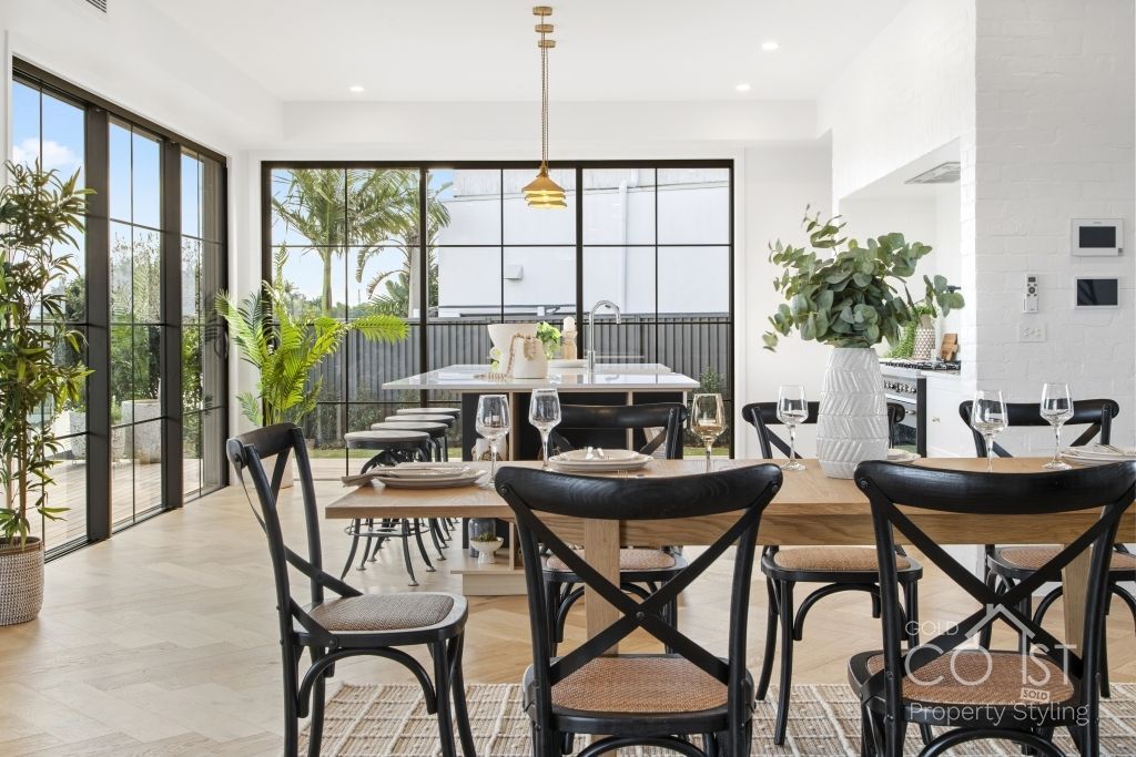 A dining room with a table and chairs and a lot of windows.