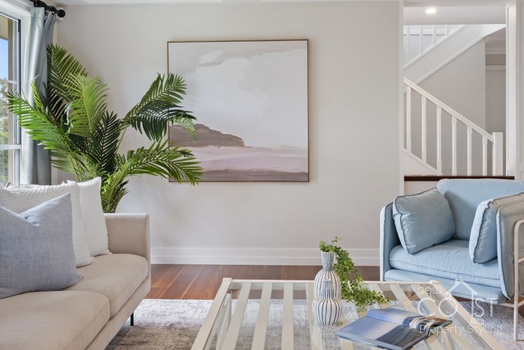 A living room with a couch , chair , coffee table and a painting on the wall.