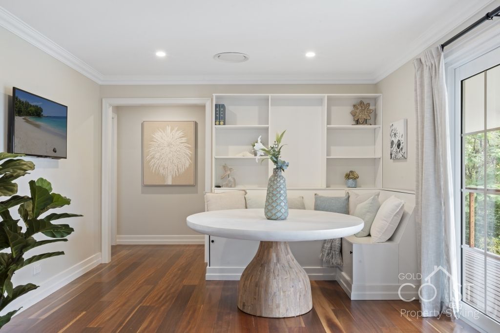 A living room with a table , couch , shelves and a television.