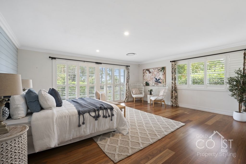 A bedroom with a large bed , chairs , lamps and a rug.