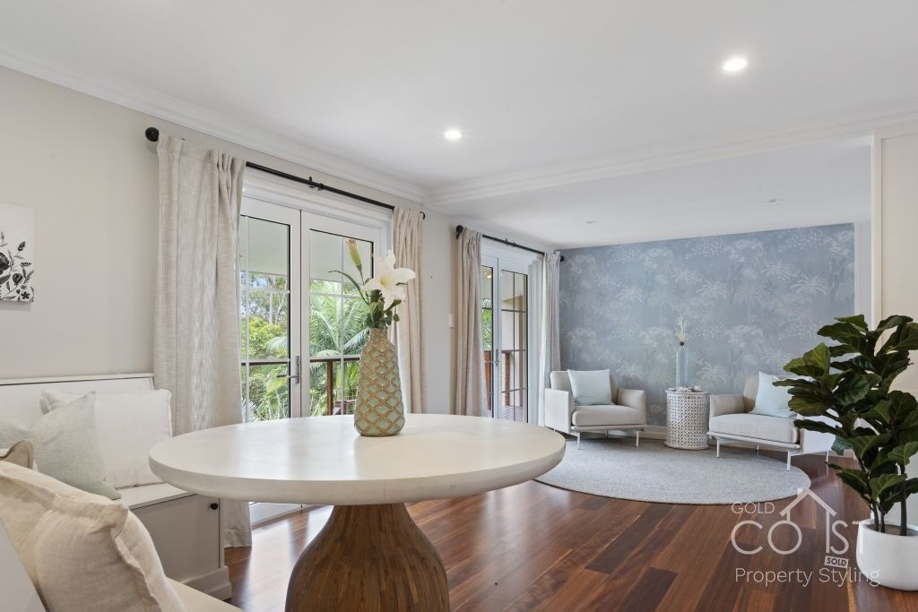 A living room with a table and chairs and a vase of flowers on it.