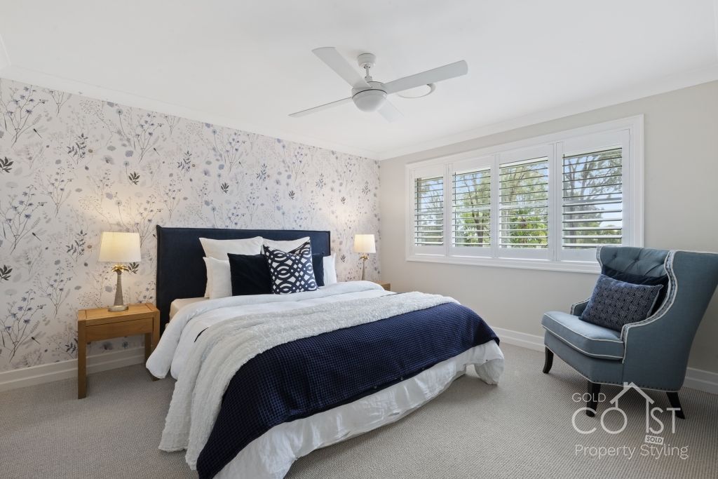 A bedroom with a bed , chair and ceiling fan