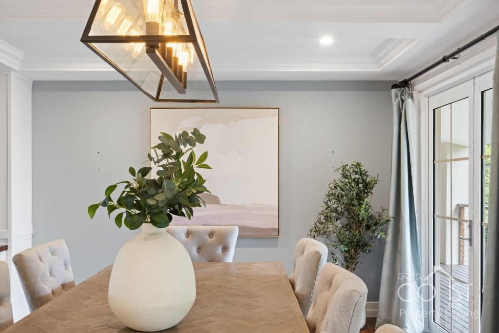 A dining room table with a vase of plants on it.