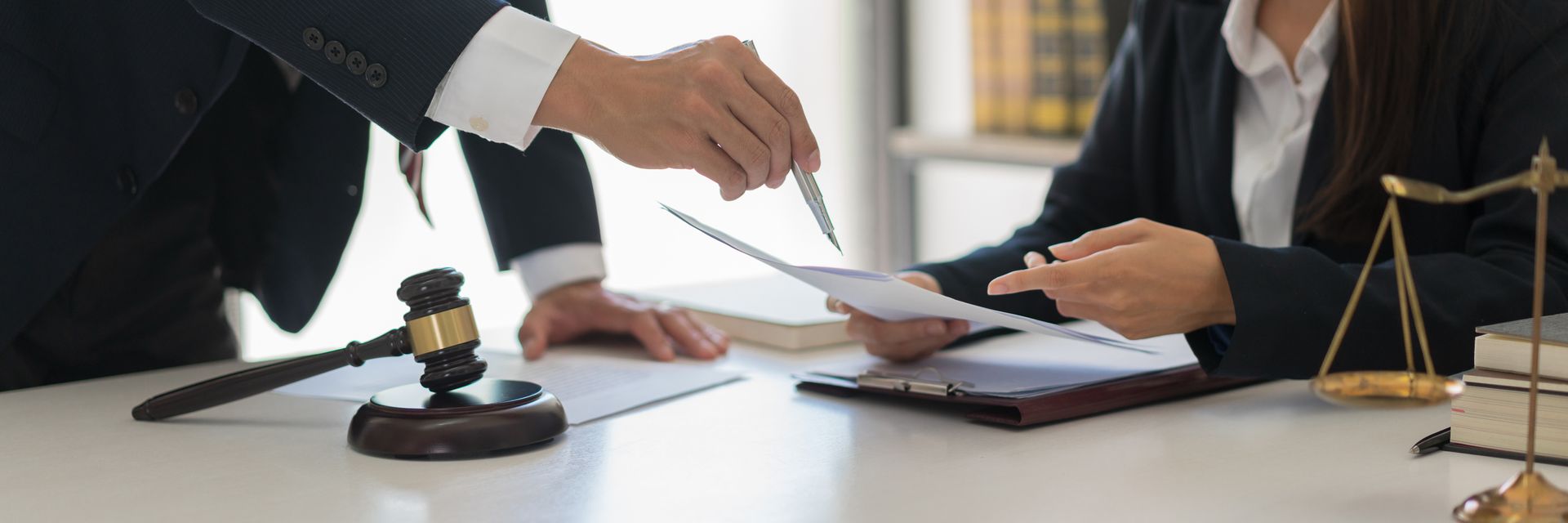 Lawyers reviewing documents in an office, with a gavel and scales of justice.
