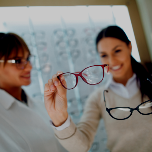 A woman is holding up a pair of glasses while another woman looks on