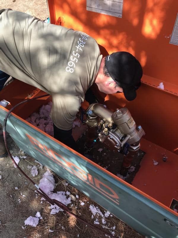 A man is working on a machine with a phone number on his back
