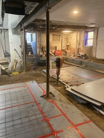 A basement under construction with a concrete floor and a hammer.