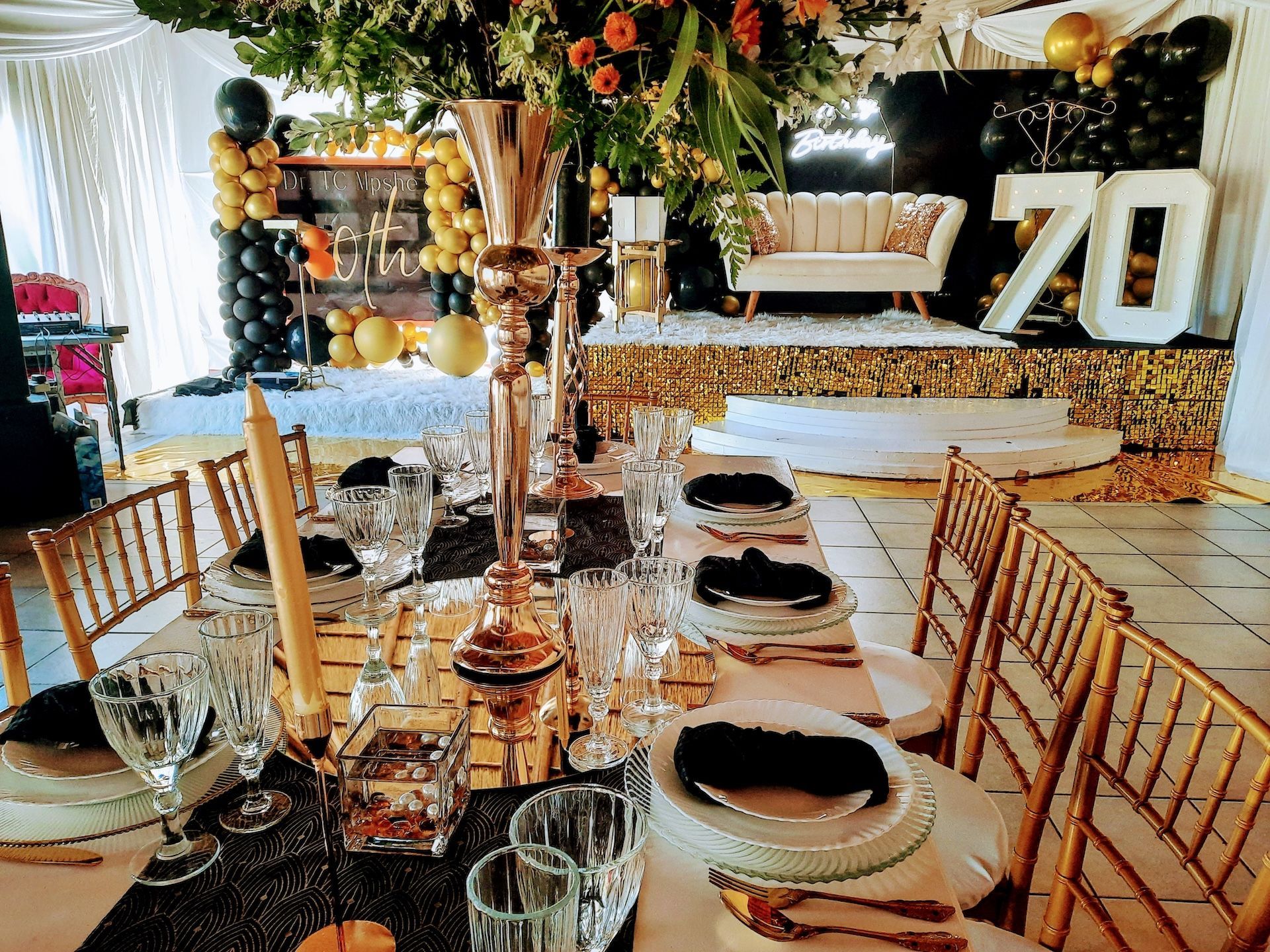 A table set for a 70th birthday party with plates , glasses , and candles.