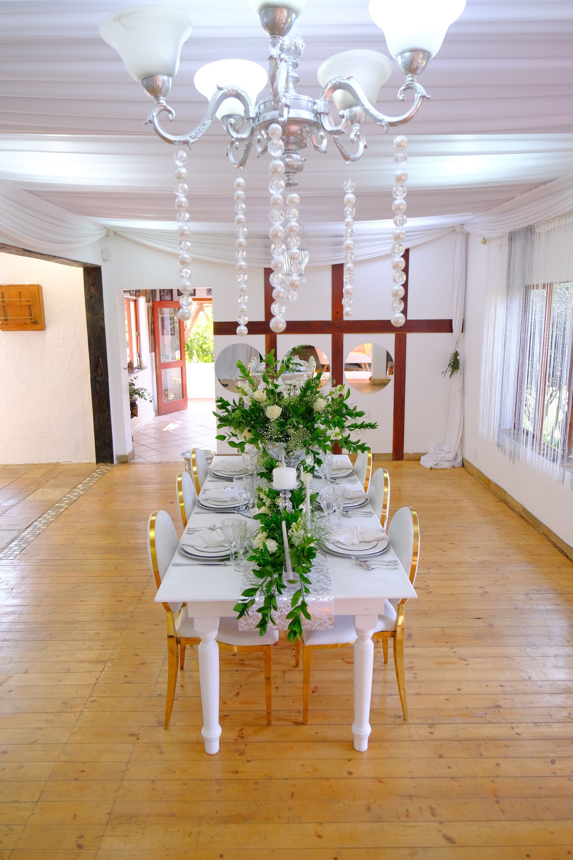 A long dining table with a chandelier hanging from the ceiling in a room.