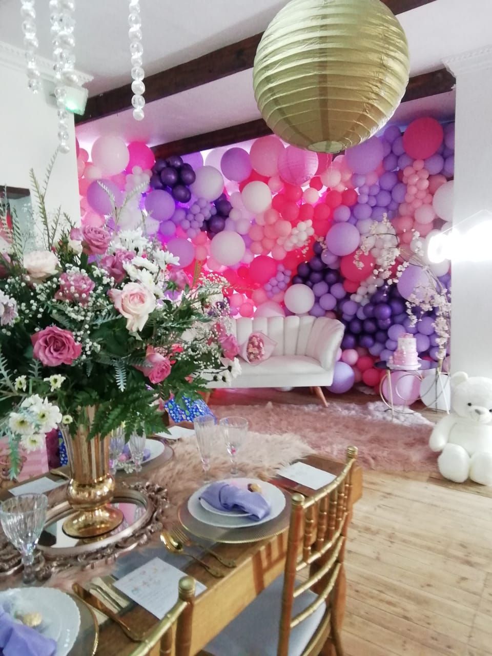 A table with plates and silverware in front of a wall of balloons