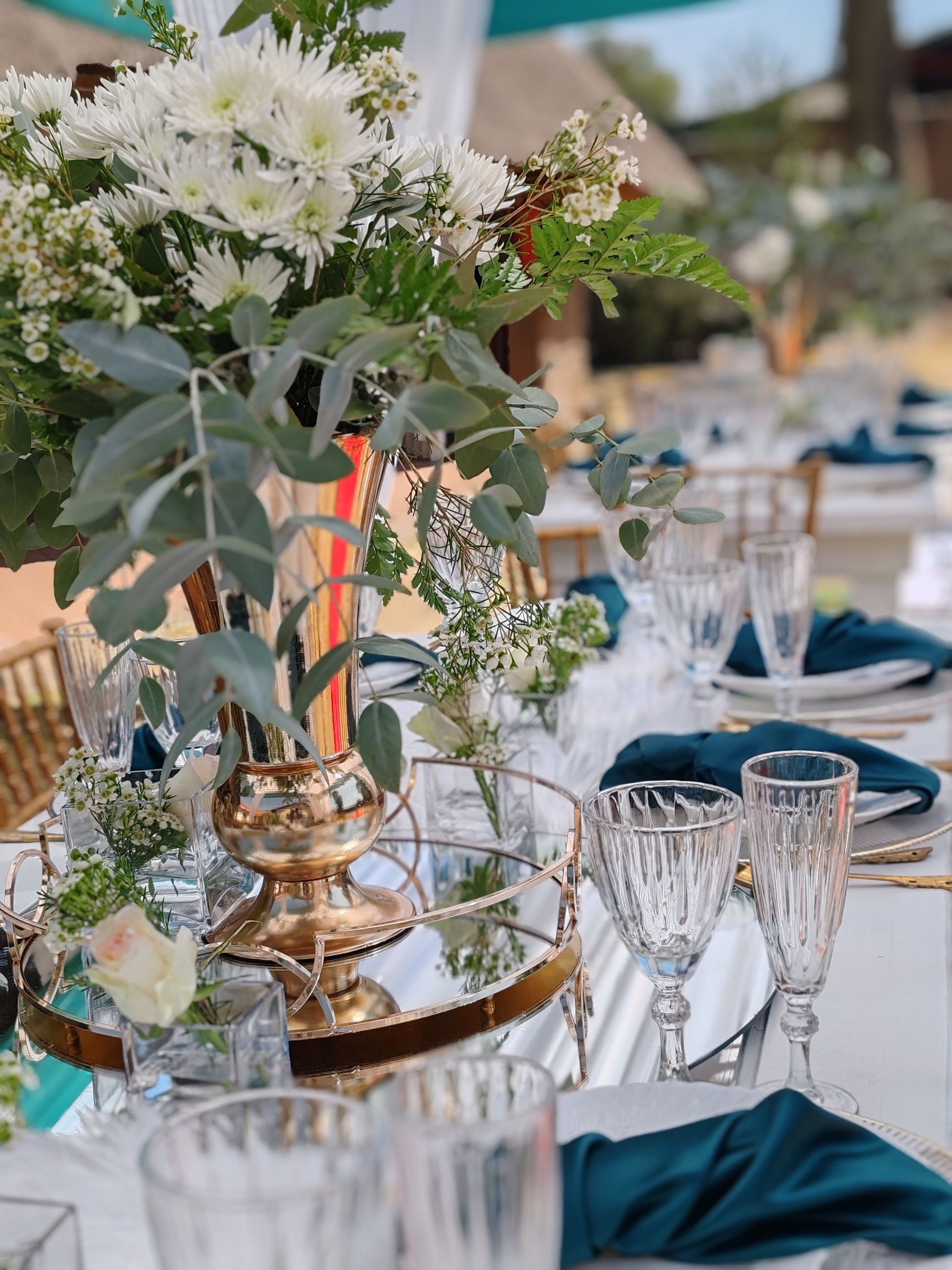 A long table with plates , glasses , and flowers on it.