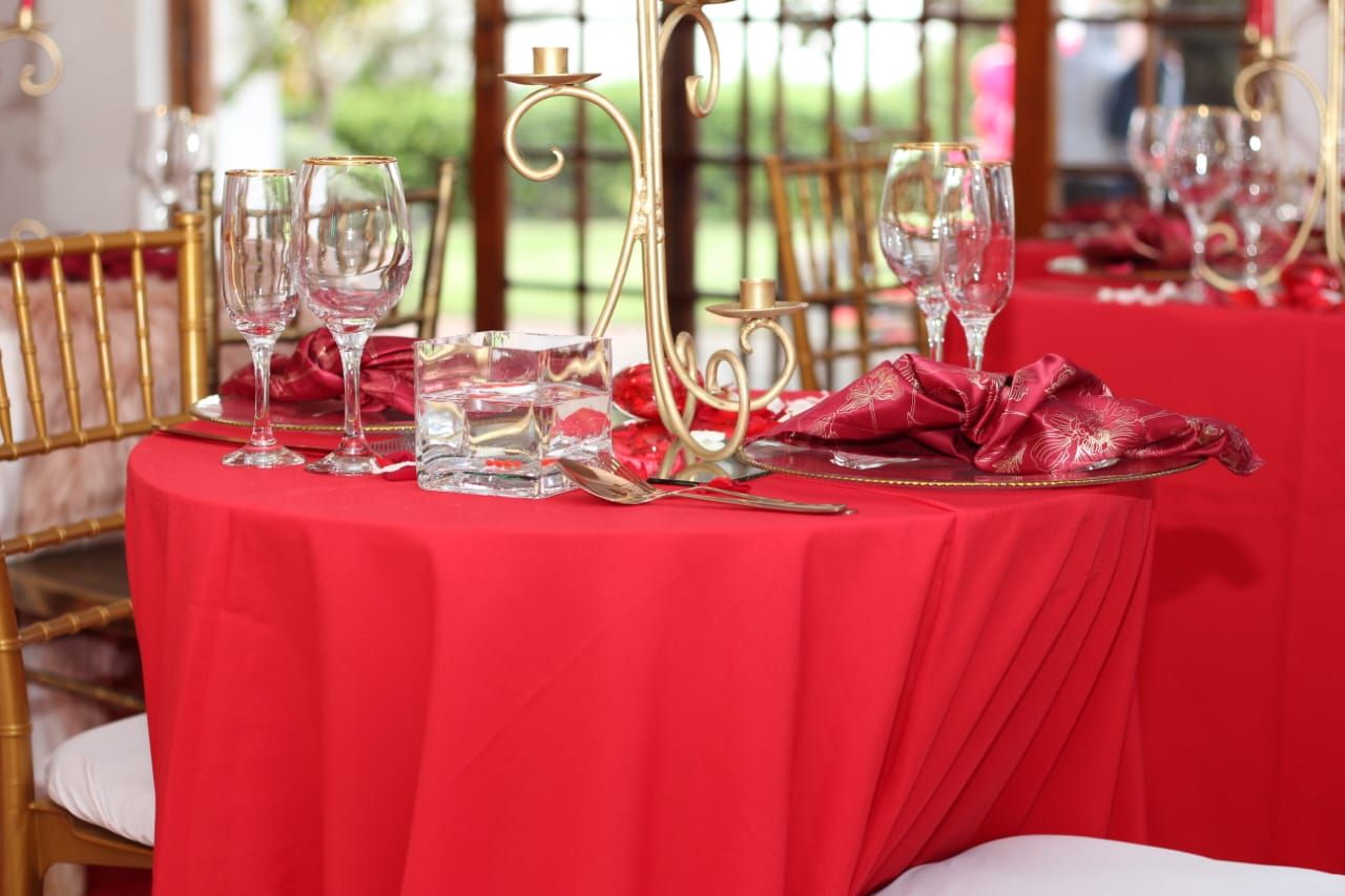 A table with a red tablecloth and glasses on it.