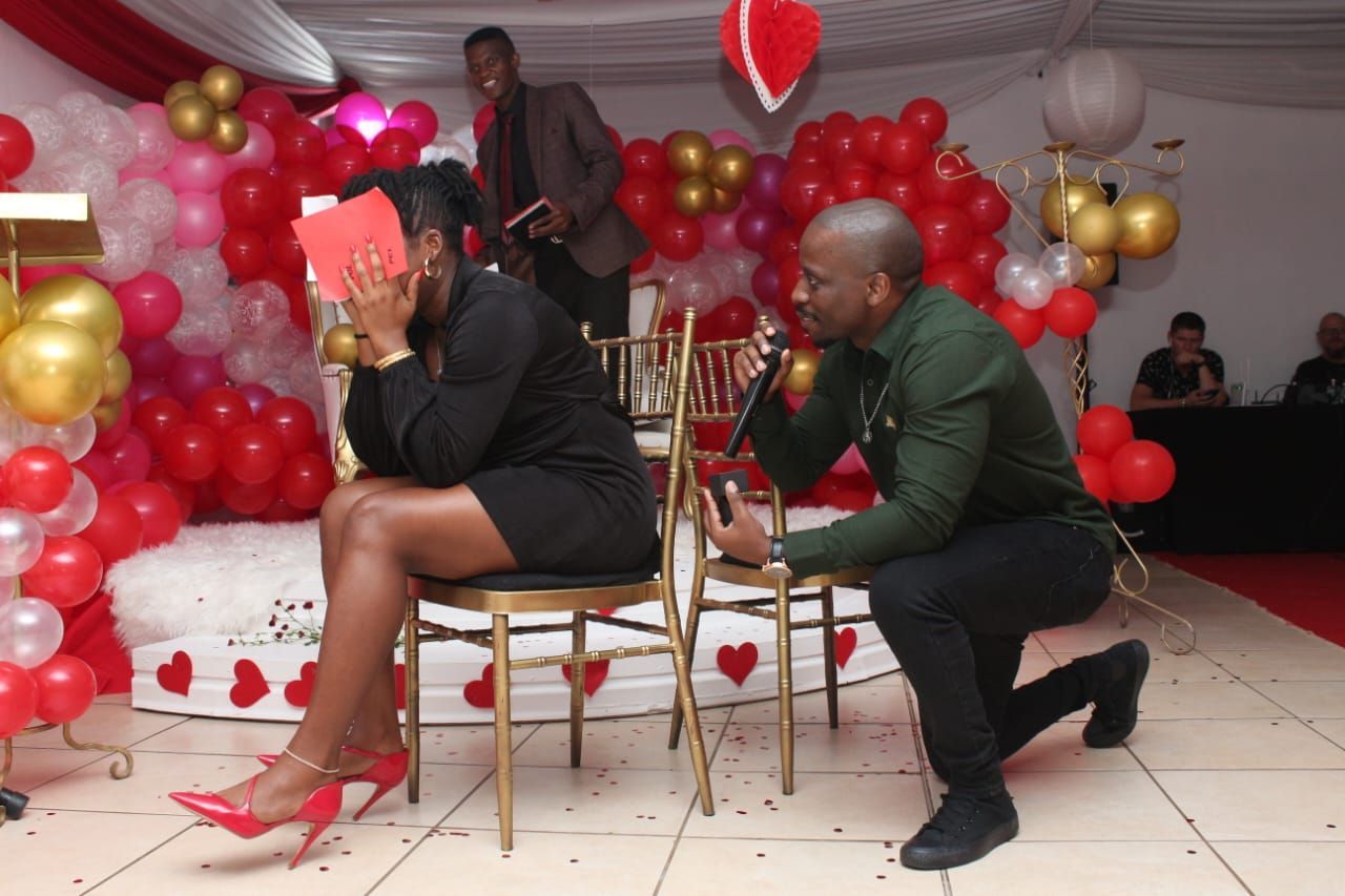 A man is kneeling down in front of a woman who is sitting in a chair.