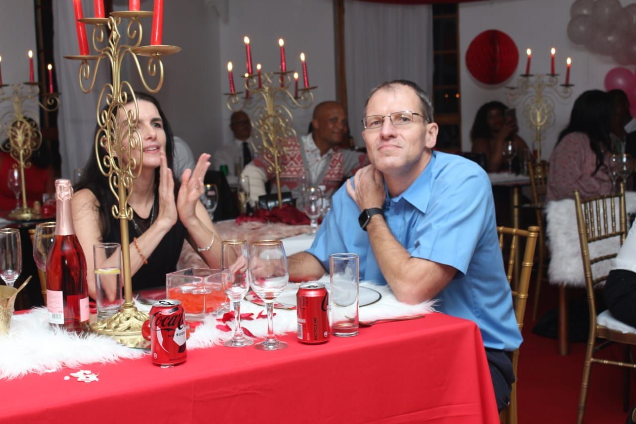 A man and a woman sit at a table with a red table cloth
