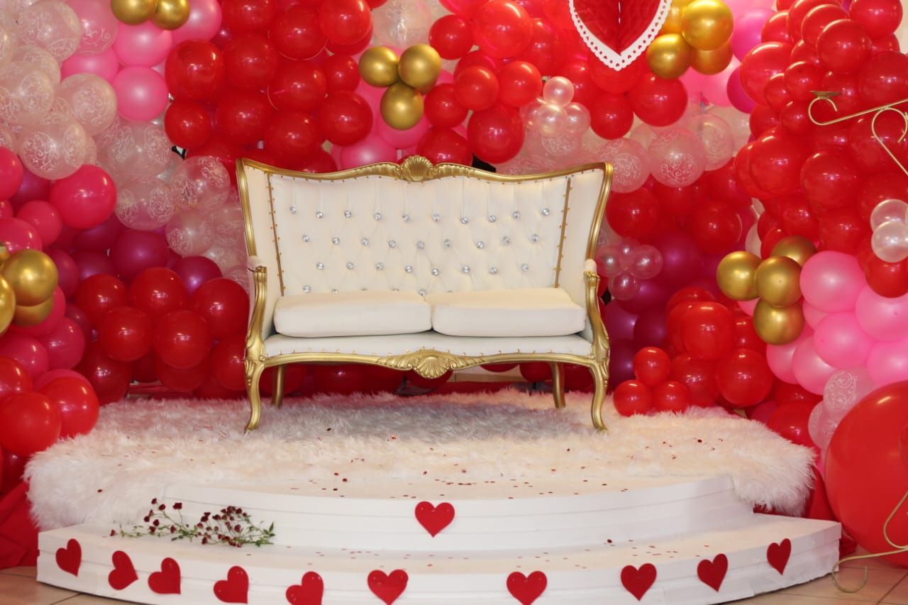 A couch is sitting in front of a wall of balloons.