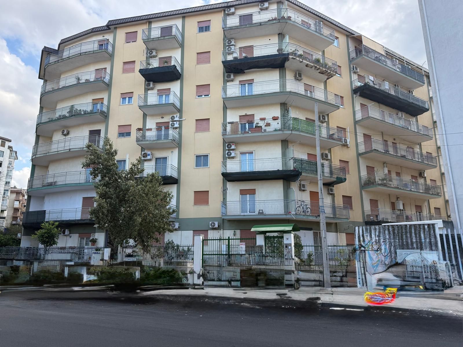 Un condominio a più piani con pareti beige e balconi sovrapposti in una giornata di sole.