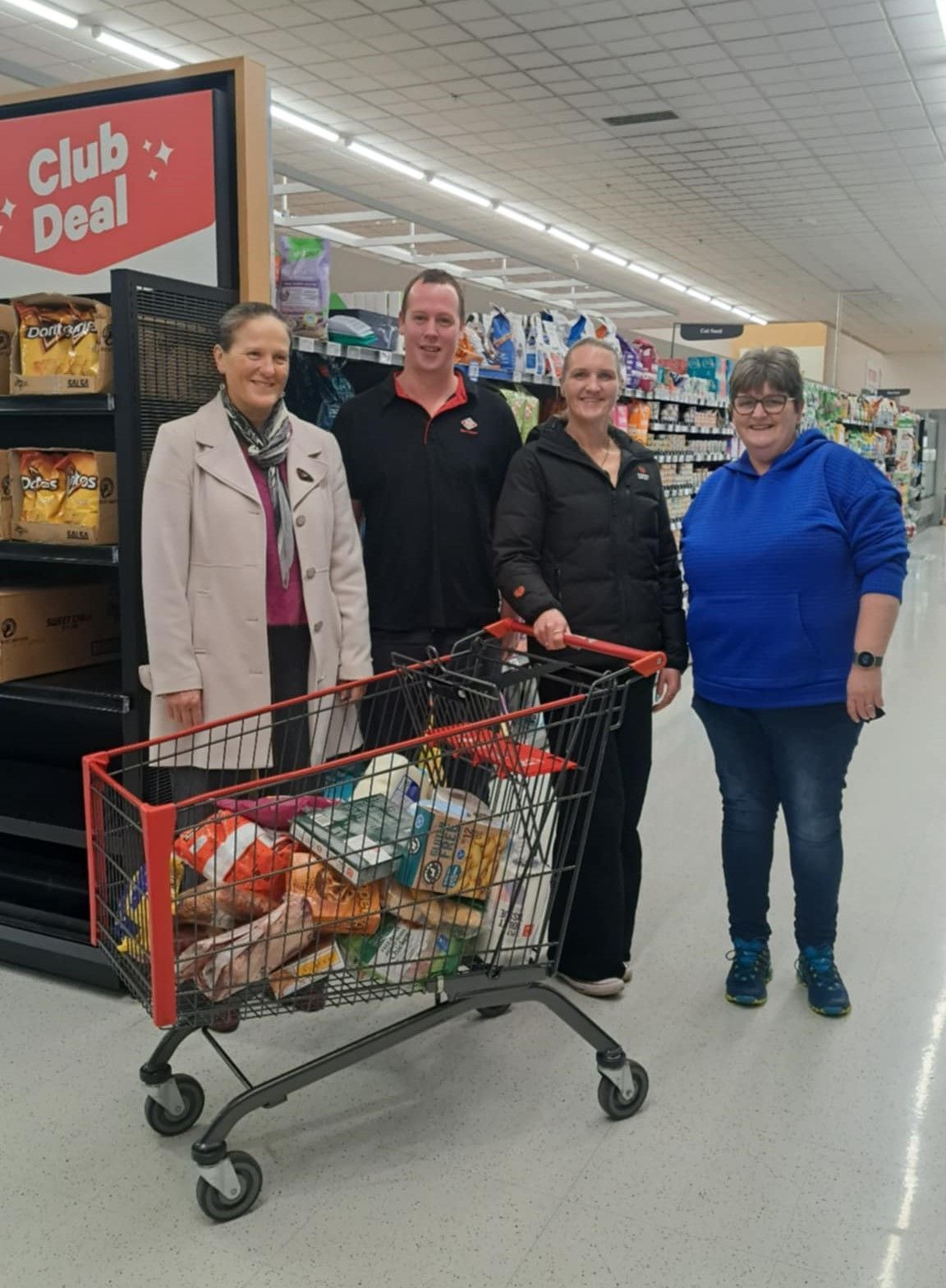 A group of people are standing in a grocery store.