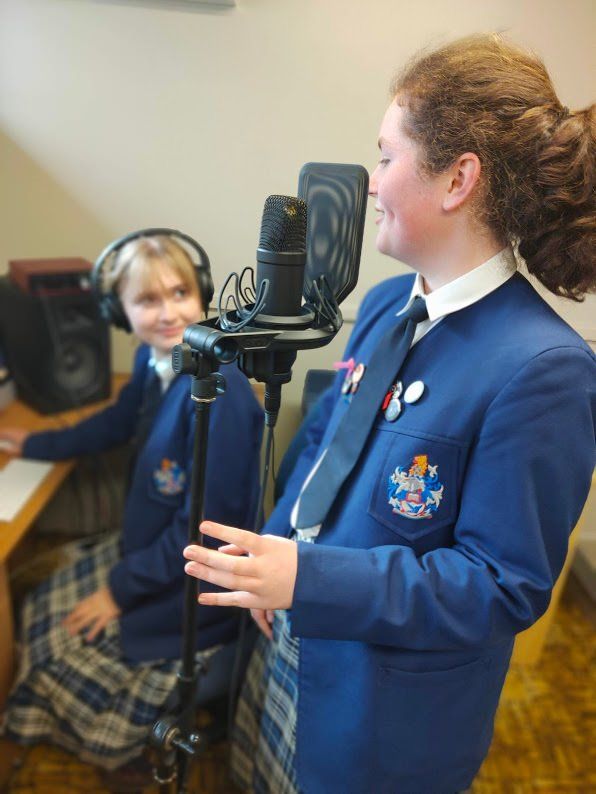 Timaru Girls Hig School | A girl in a blue jacket and tie stands in front of a microphone