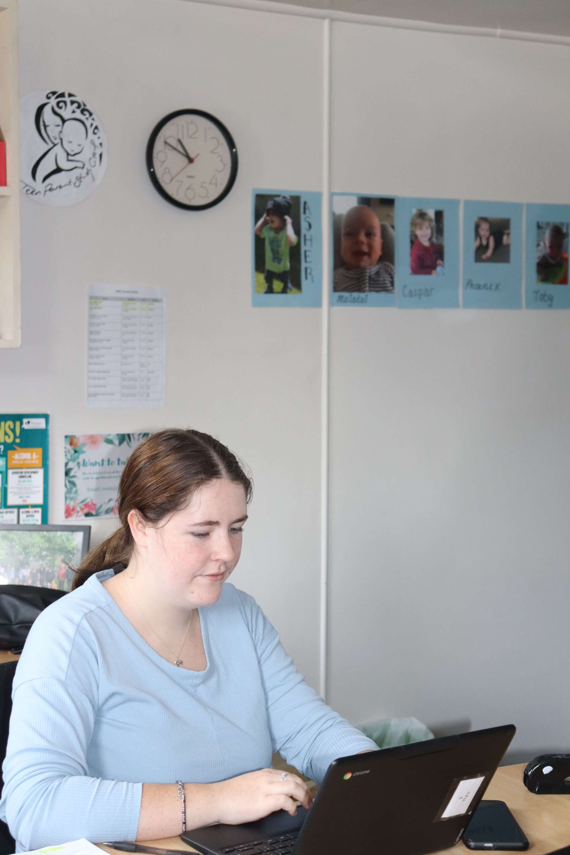 A woman is sitting at a desk using a laptop computer.