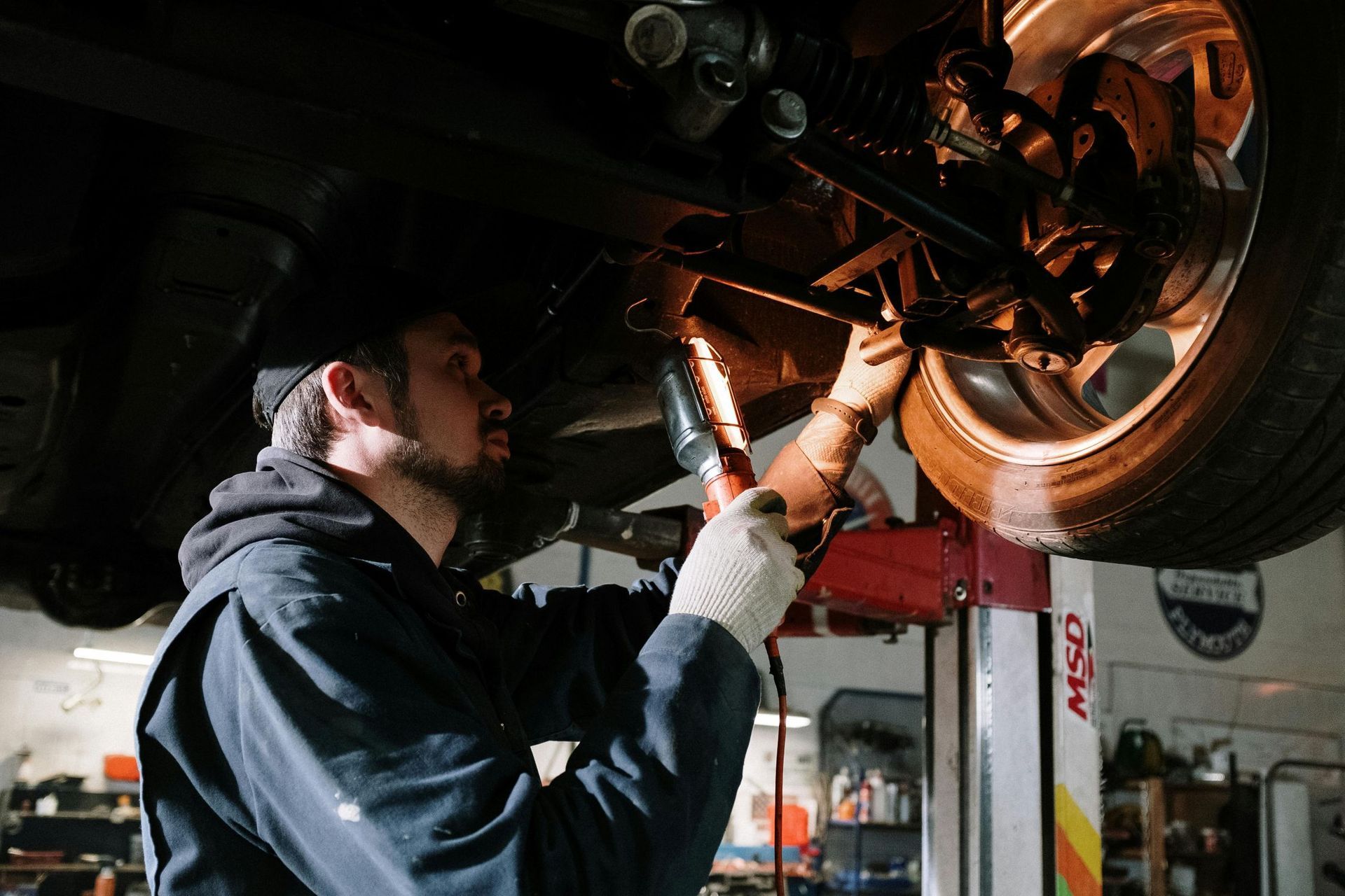 male mechanic fixing bottom of car