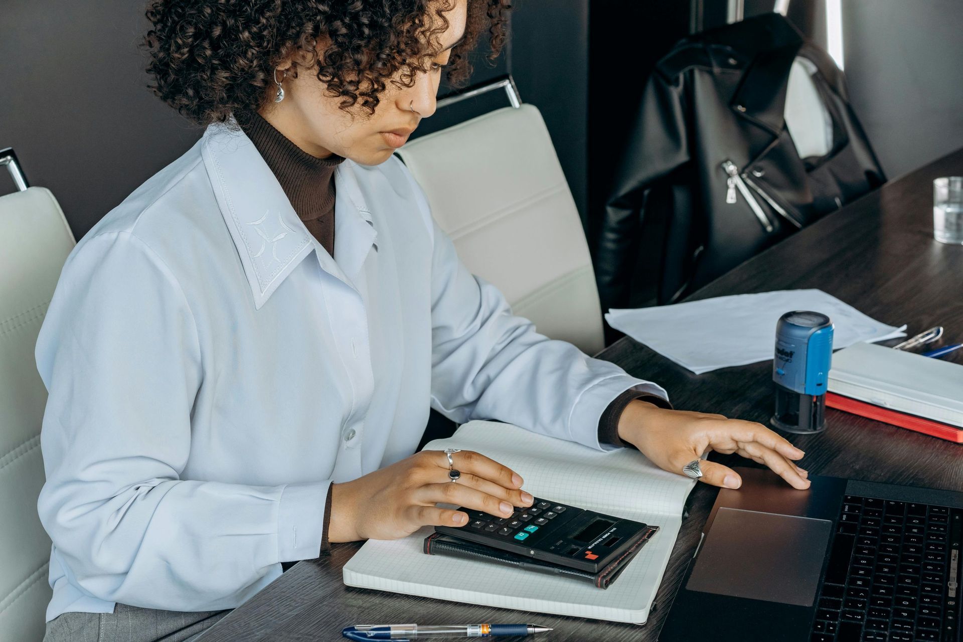 Ipswich business owner reviewing bookkeeping records and calculating expenses at desk with calculato