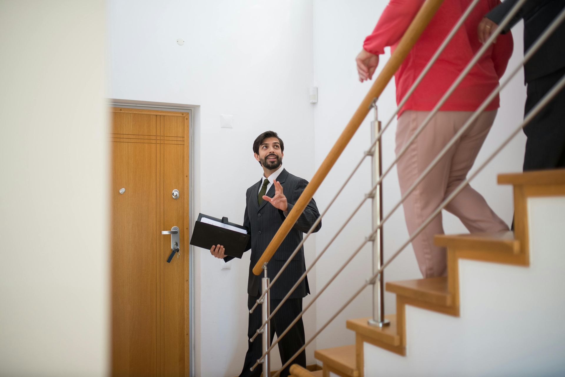 Two people on a stairwell, one holding a briefcase and talking to another descending the stairs.