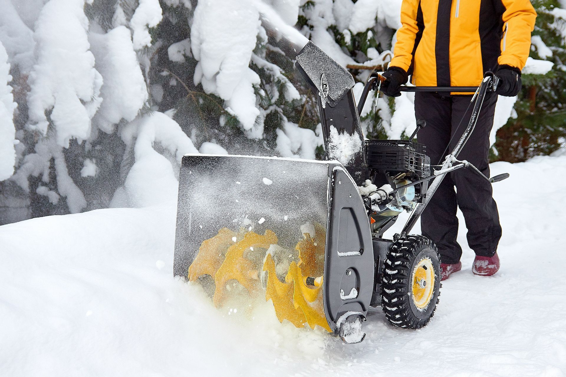 A person is using a snow blower to clear snow from a sidewalk.