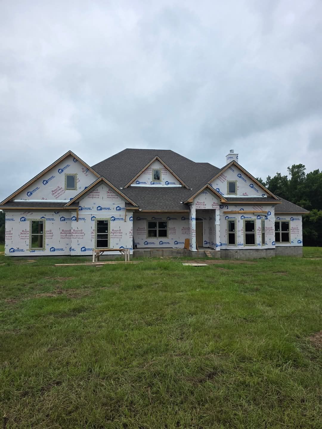 Gray house with white trim, dormers, and an outdoor seating area on a green lawn.