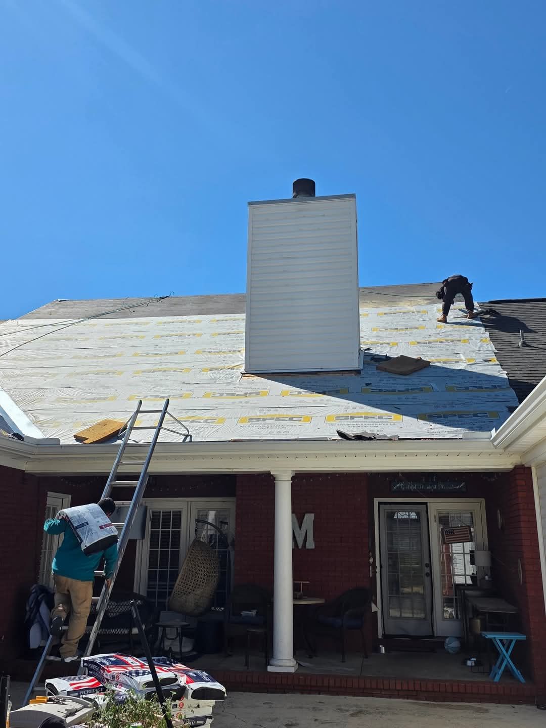 Ranch-style house with gray siding, a three-car garage, and a well-manicured lawn under a blue sky with fluffy clouds.