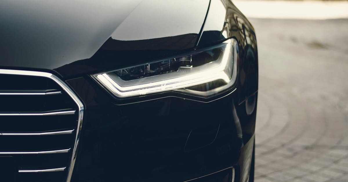 A close up of a black car 's headlight on a cobblestone street.