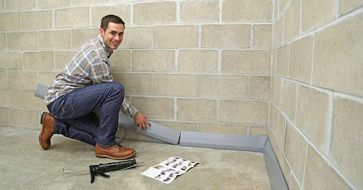 Installing basement leak repair drainage system along the wall.