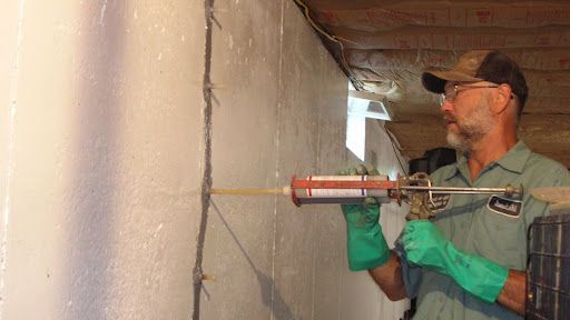 Professional sealing foundation crack during basement leak repair.