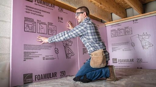 Crawl space insulation installer applying foam board insulation to walls