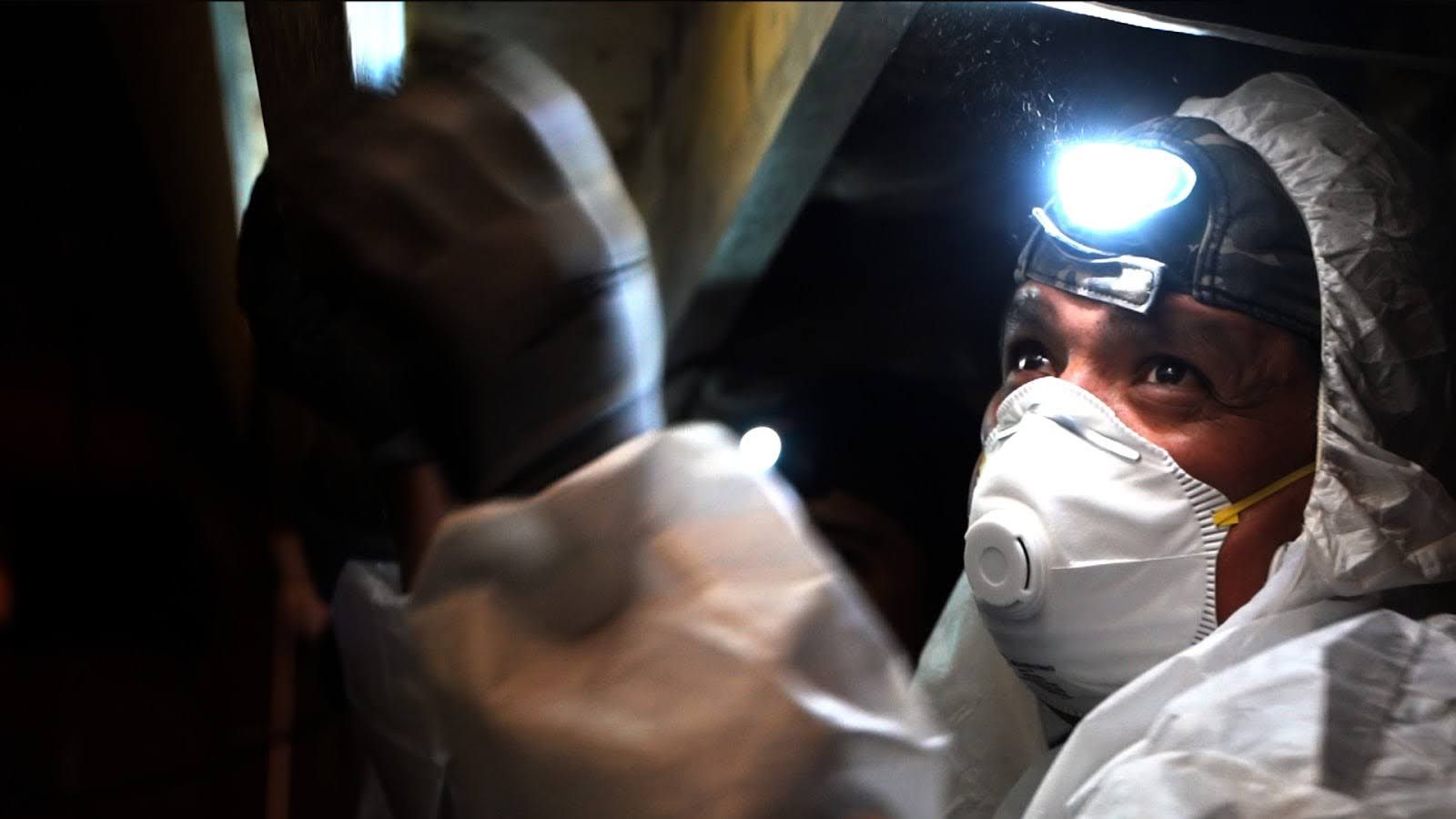 Professional crawl space repair technician working in protective gear.