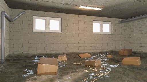 Flooded basement with floating cardboard boxes, indicating severe water damage.