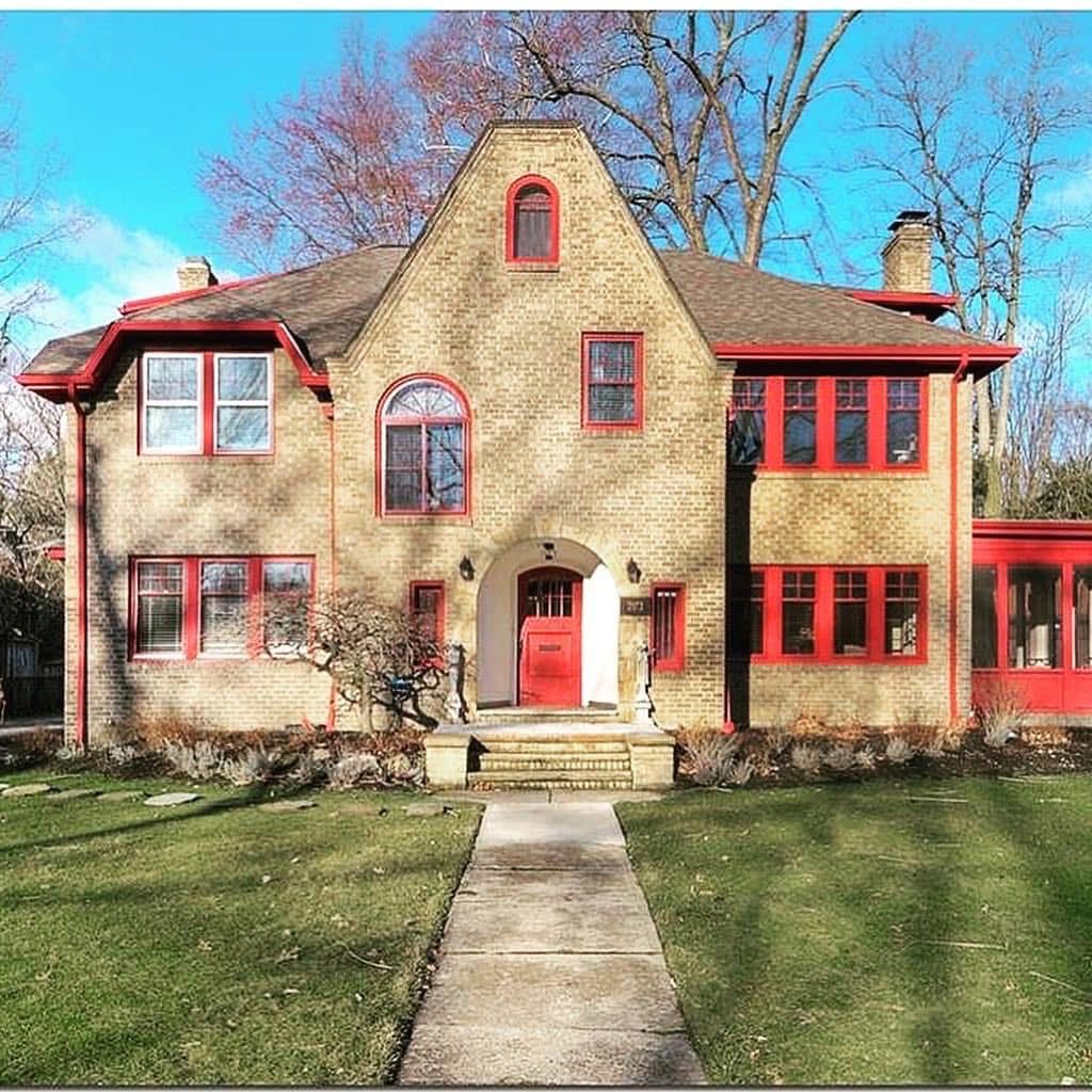 House with a covered porch, red brick accents, and a driveway, under a blue sky.