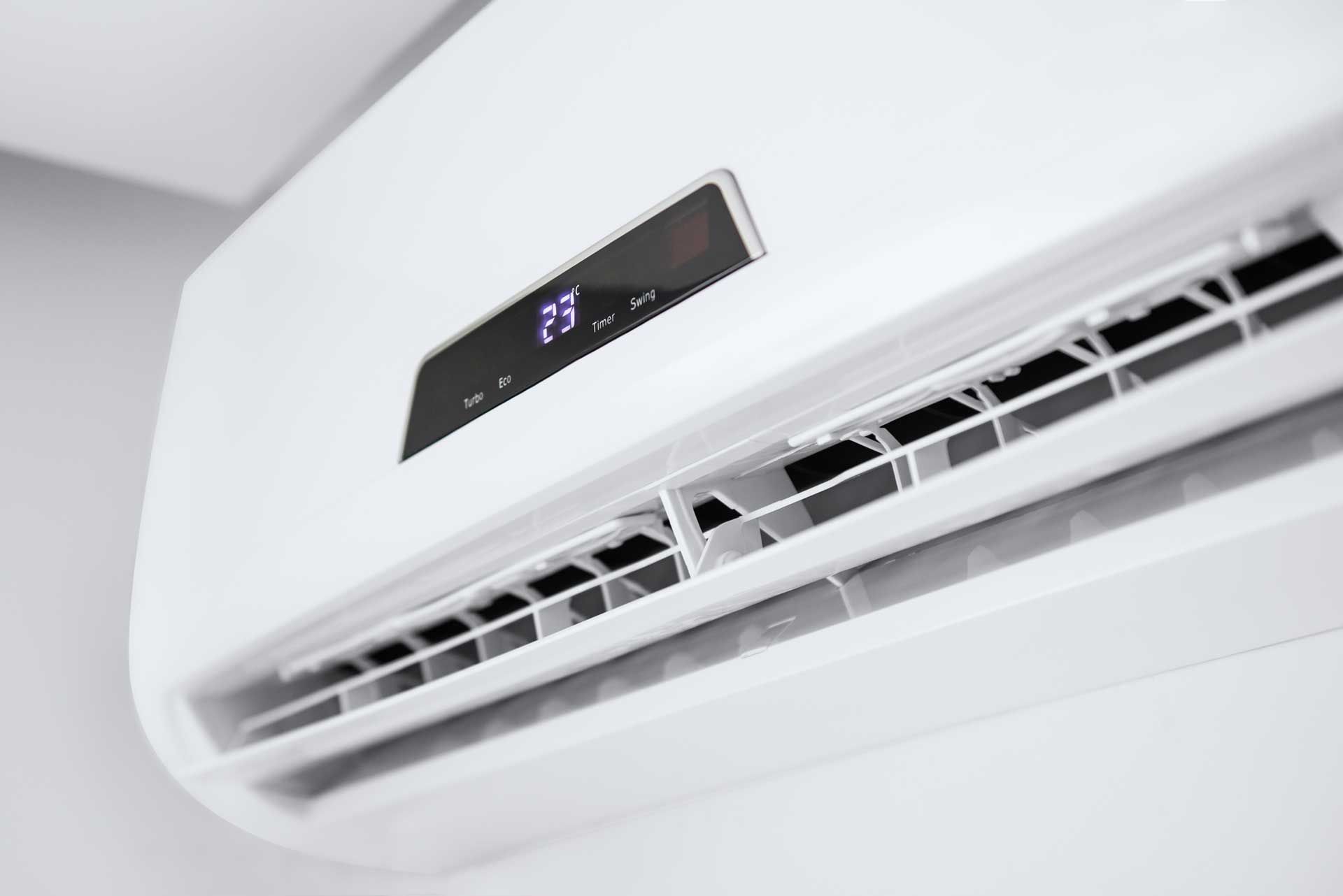A close up of a white air conditioner on a wall.