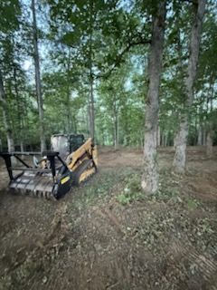 Orange construction vehicle, close-up of the tread, blurred background with rocks and trees.