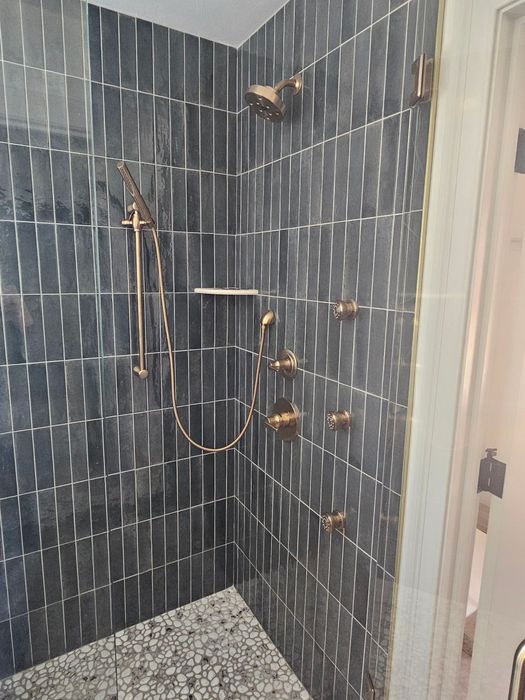A bathroom with a walk in shower and a shower head.