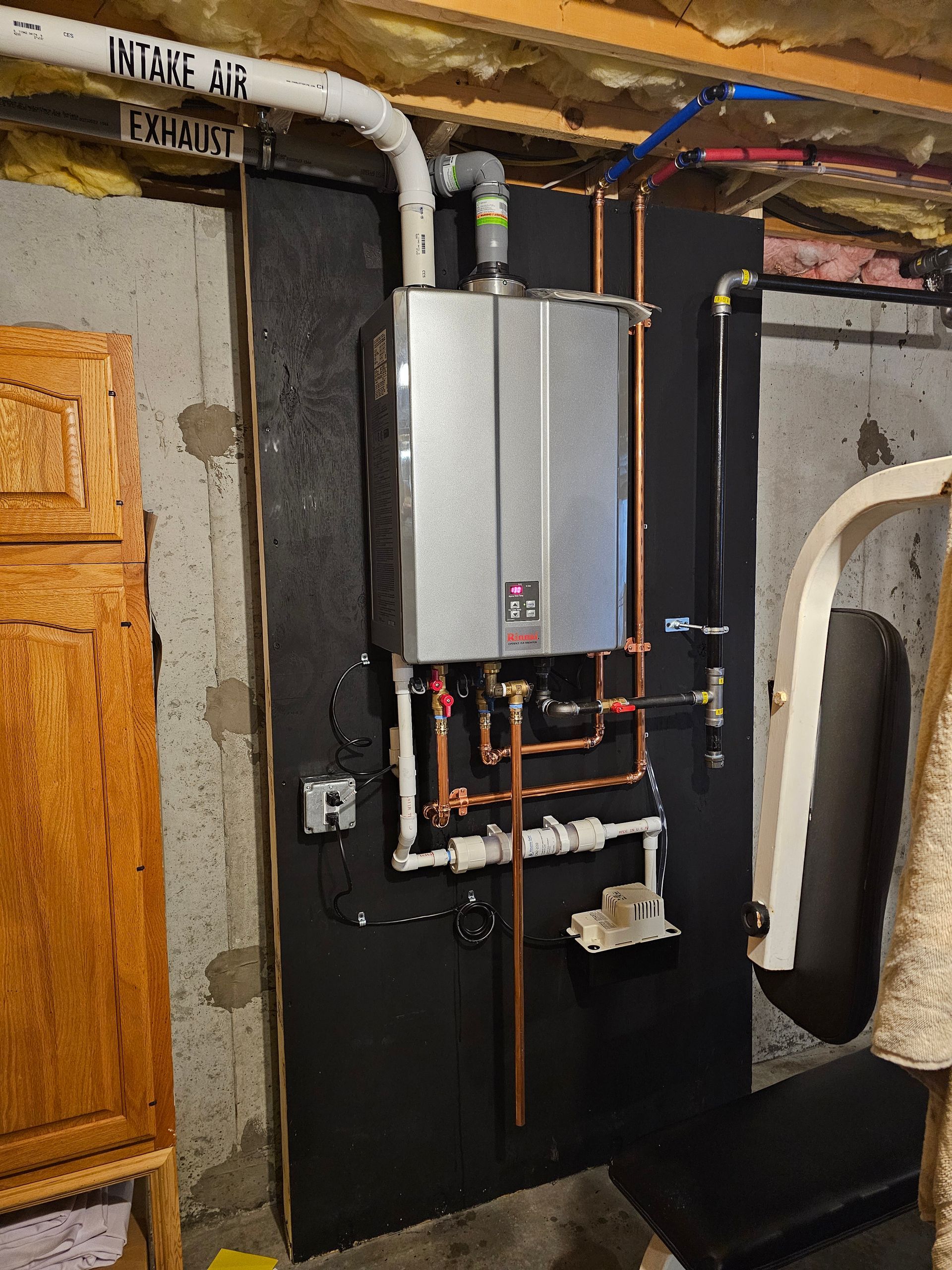 A water heater is mounted to a wall in a basement.