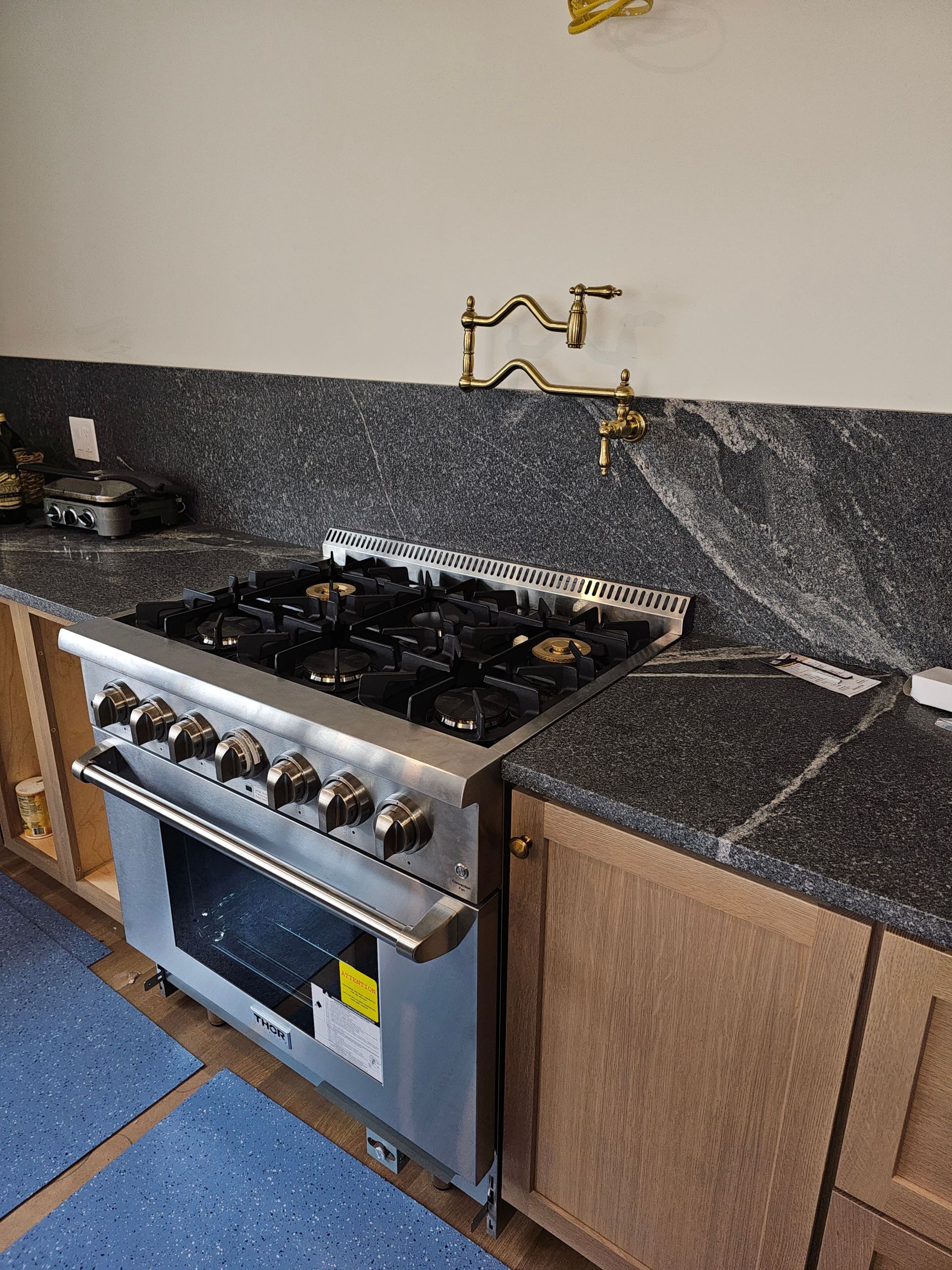 A kitchen with a stove top oven and granite counter tops.