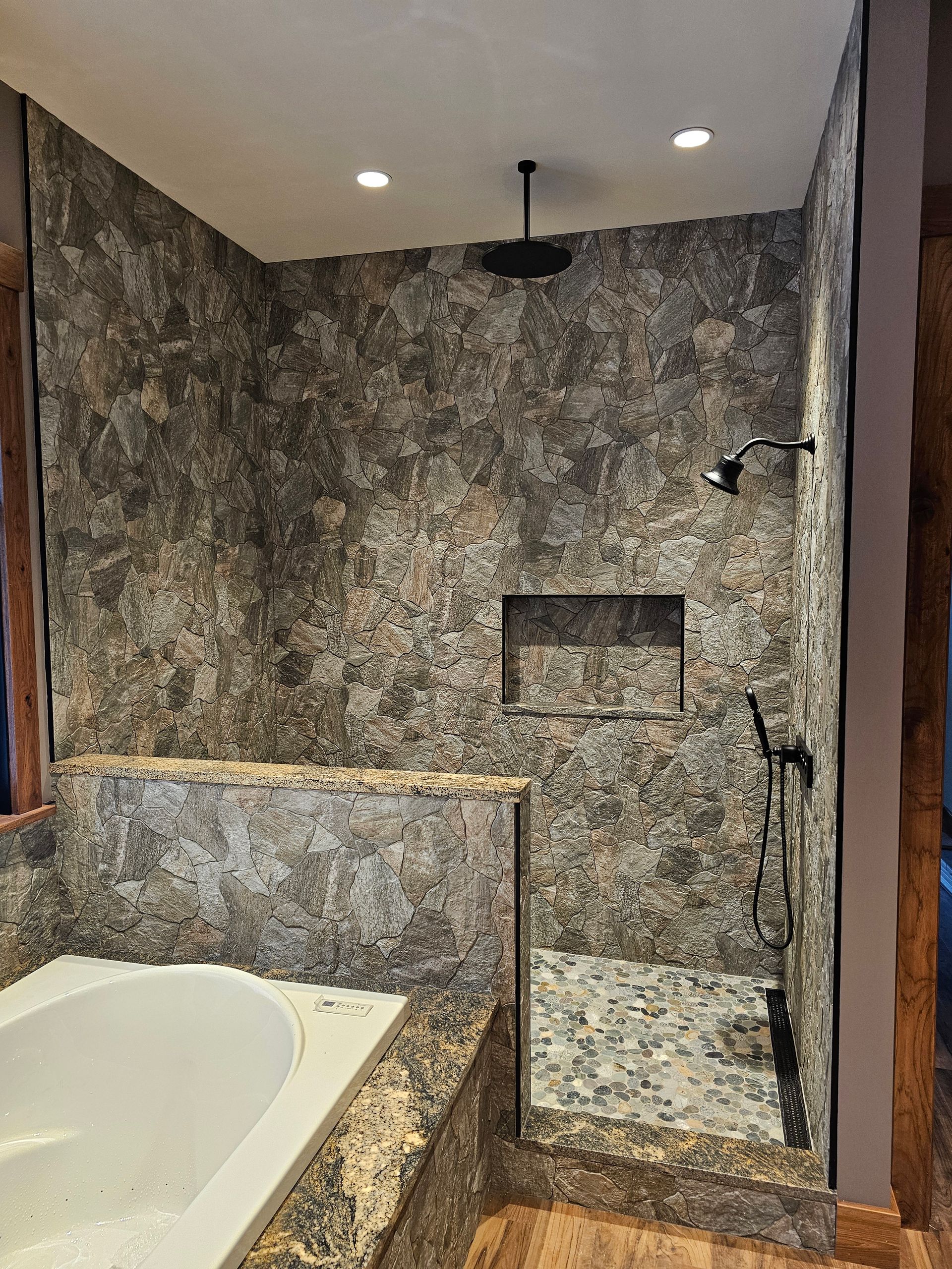 A bathroom with a walk in shower and a shower head.
