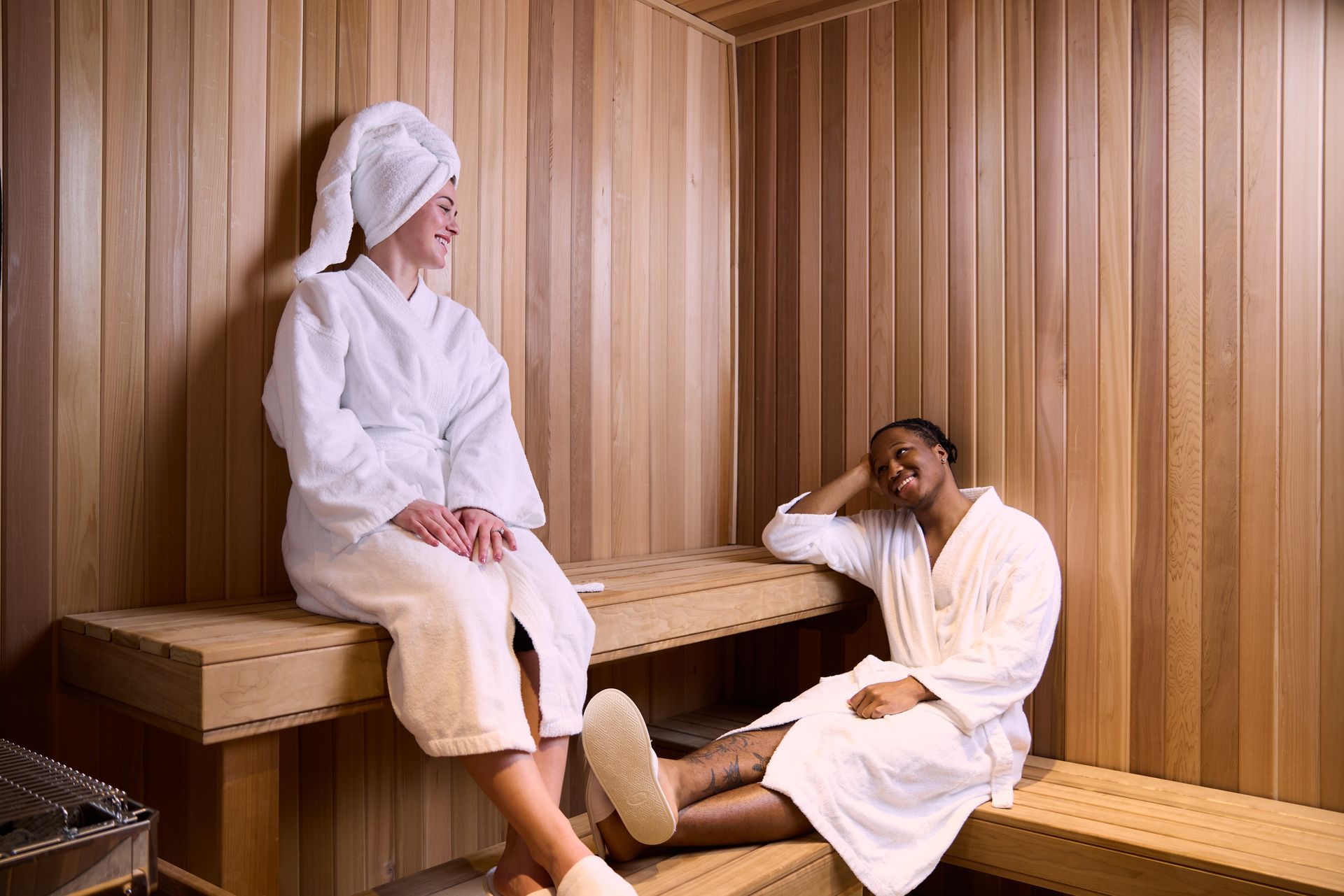 A woman is laying in a wooden sauna wrapped in a towel.