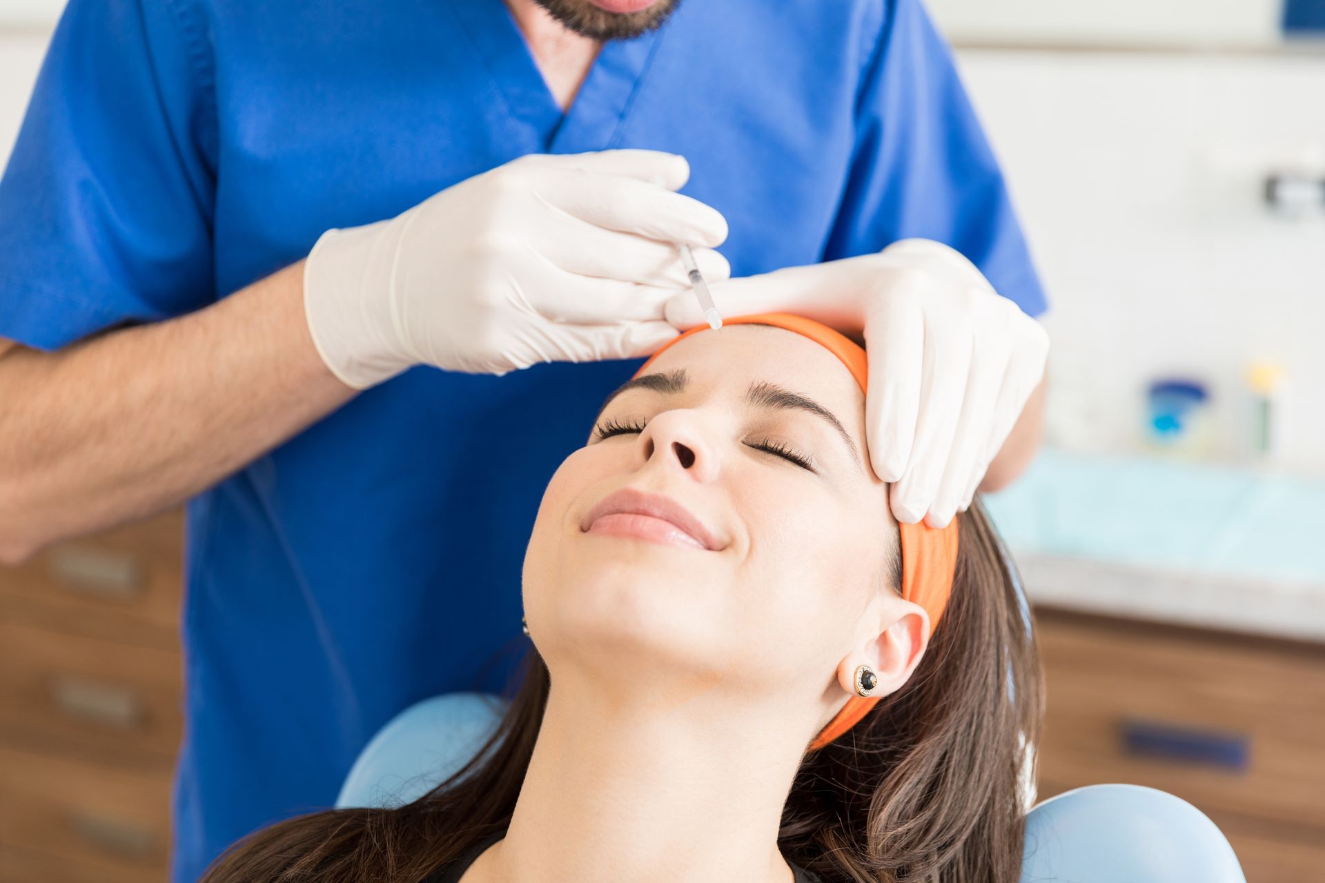 A woman is sitting in a dental chair talking to a dentist.