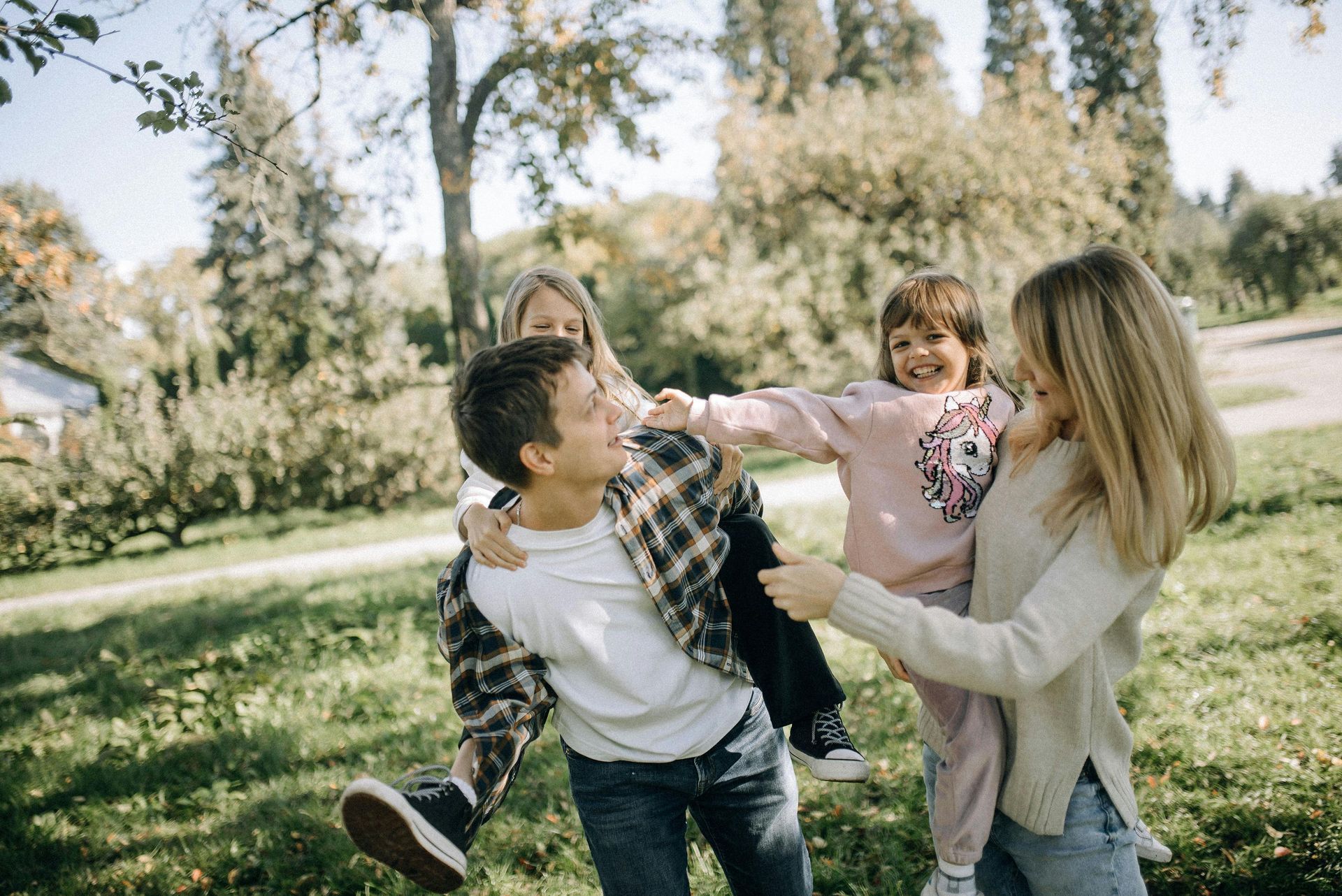 Man, woman, and two children outside playing with one child on the man's back