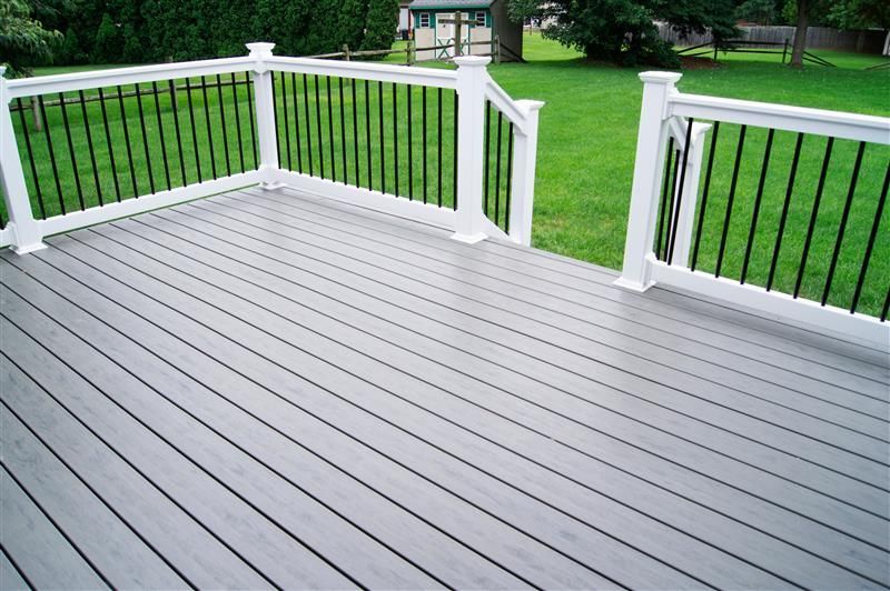 Gray composite deck with white railing, black balusters, and green lawn.